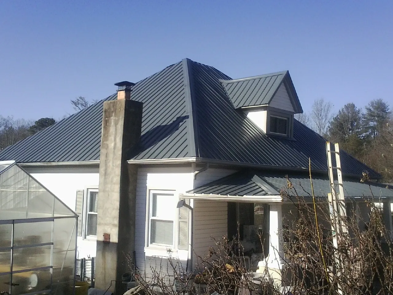 Dark blue standing seam metal roof on a white farmhouse with dormer — Slate & Tile Roof Repair by Roofing Brothers in Oak Grove