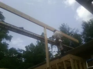 Carpenter setting a ridge beam over a new addition frame — Ice Dam Removal by Roofing Brothers in Oak Grove