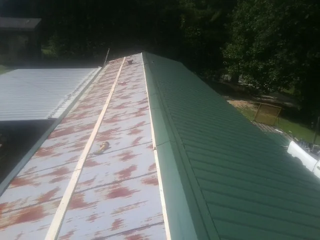 Old rusted panels beside newly installed green metal roofing — Wind Damage Roof Repair by Roofing Brothers in Oak Grove