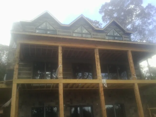 Dormers and porch framing on a large log home under construction — Roof Coating work by our crew in Oak Grove