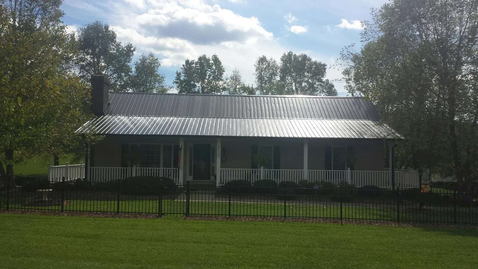 Gray metal roof on a brick ranch with a full width front porch — Gutter Guard Installation work by our crew in Oak Grove