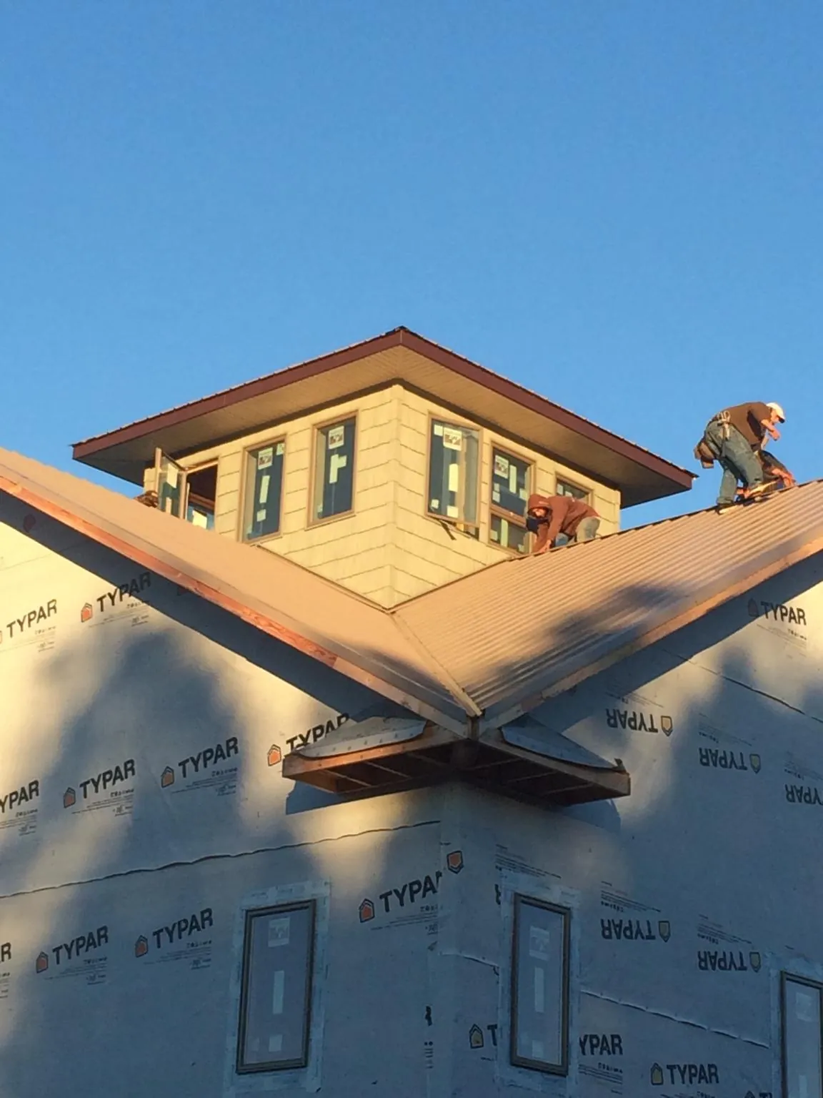 Roofers working around a rooftop cupola on a new metal roof at sunset — Roof Waterproofing in Oak Grove by Roofing Brothers